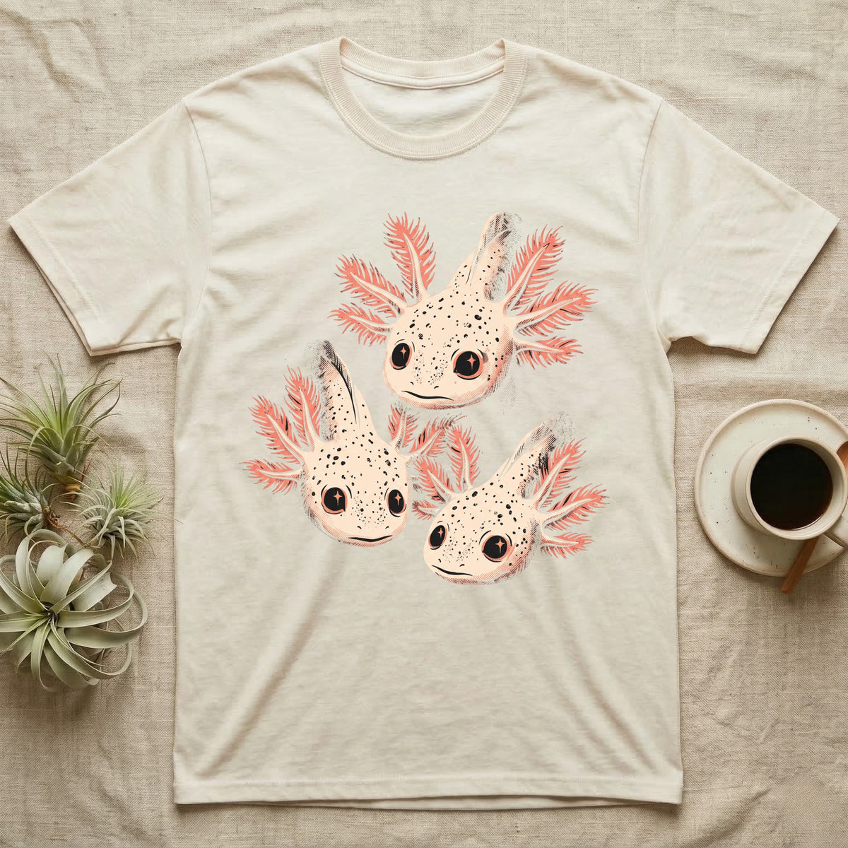 Vintage comic screen-print illustration of three axolotls clustered together with coral feathery gills and sparkling star-highlighted eyes, graphic-only, no text. — shown on a Natural tee.