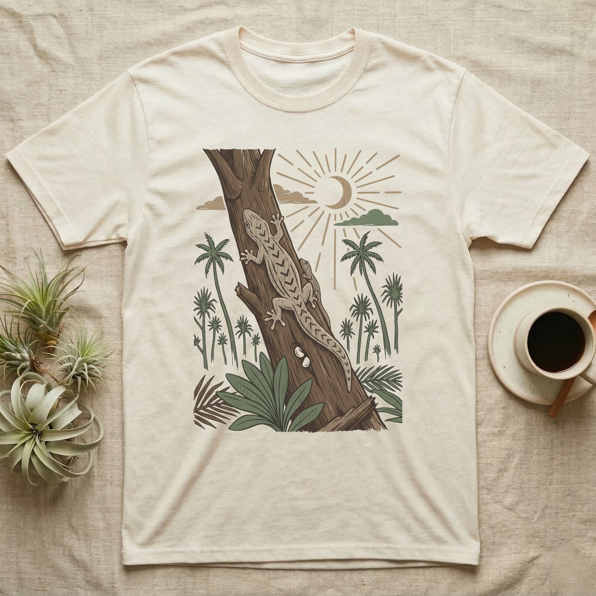 Mourning Gecko Home Range T-Shirt in Natural — Woodcut-style illustration of two mourning geckos on a palm trunk with a pair of eggs in the bark and palms behind, no on-shirt text.