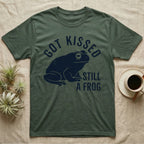 Tree Frog Kissed T-Shirt in Military Green — Worn navy silhouette of a dumpy White's tree frog under the words Got Kissed Still A Frog