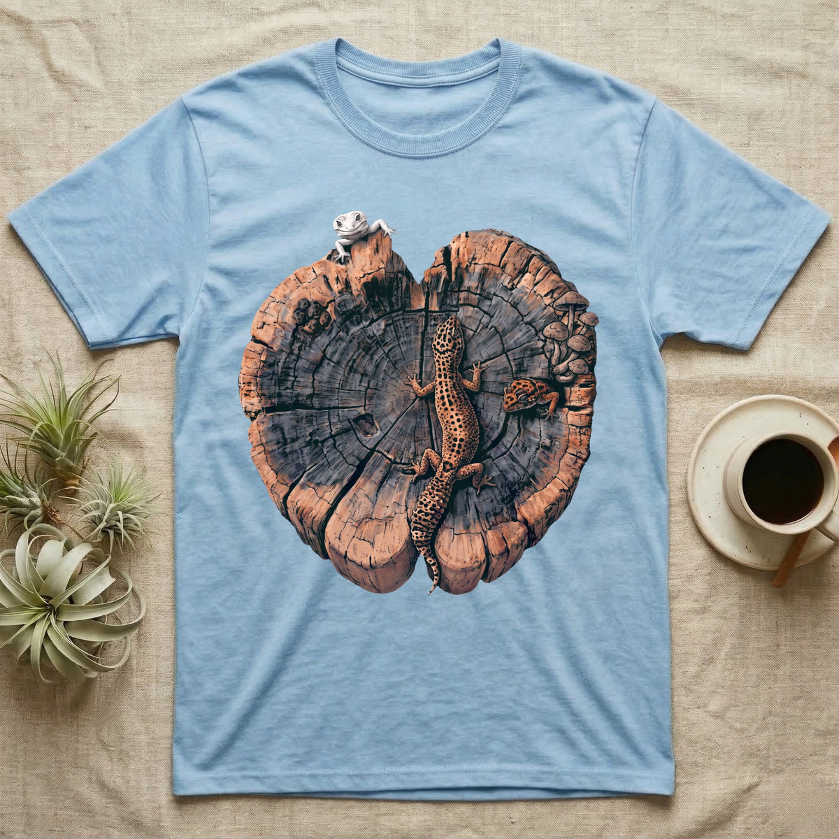 Leopard Gecko Stump Trio T-Shirt in Light Blue — Three leopard geckos including a leucistic white morph on a cross-section log slab of amber growth rings with mushrooms, no on-shirt text.
