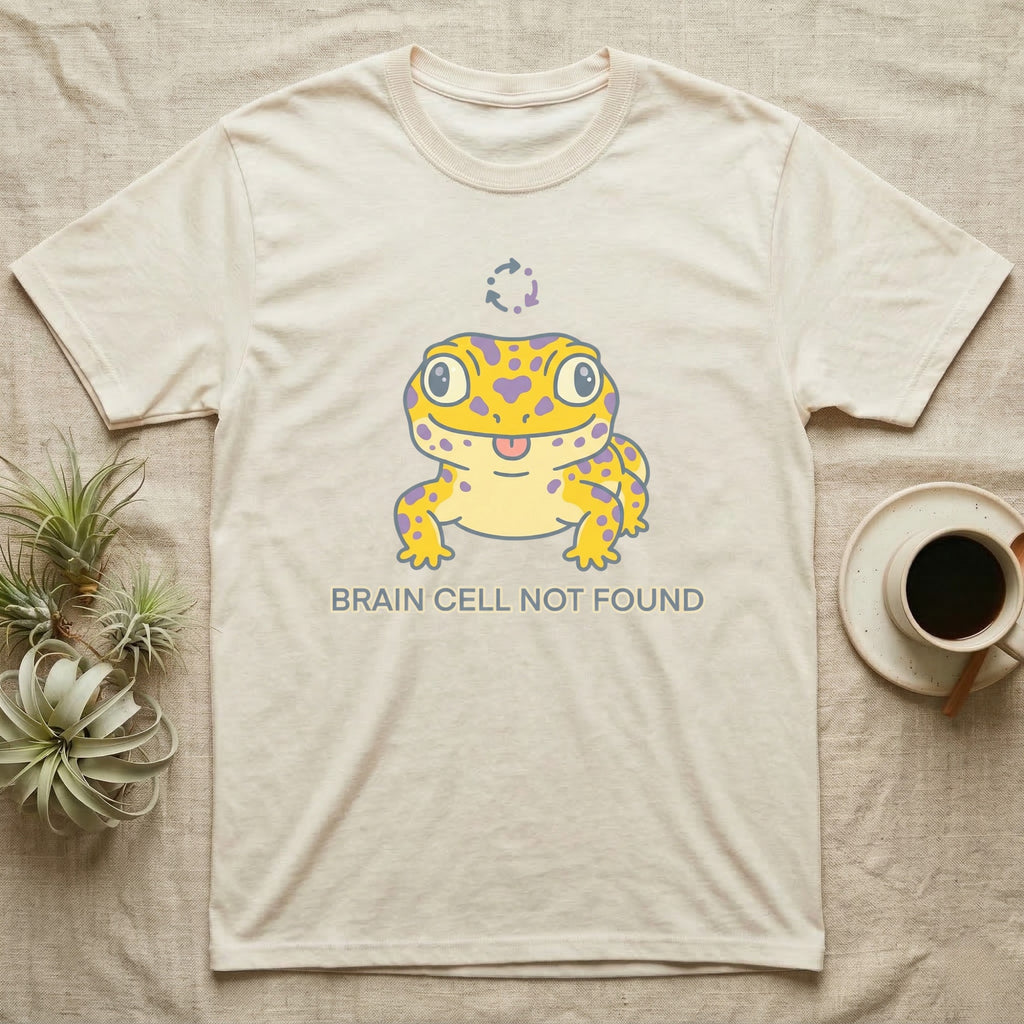 Cream t-shirt with yellow cartoon gecko and "BRAIN CELL NOT FOUND" text.