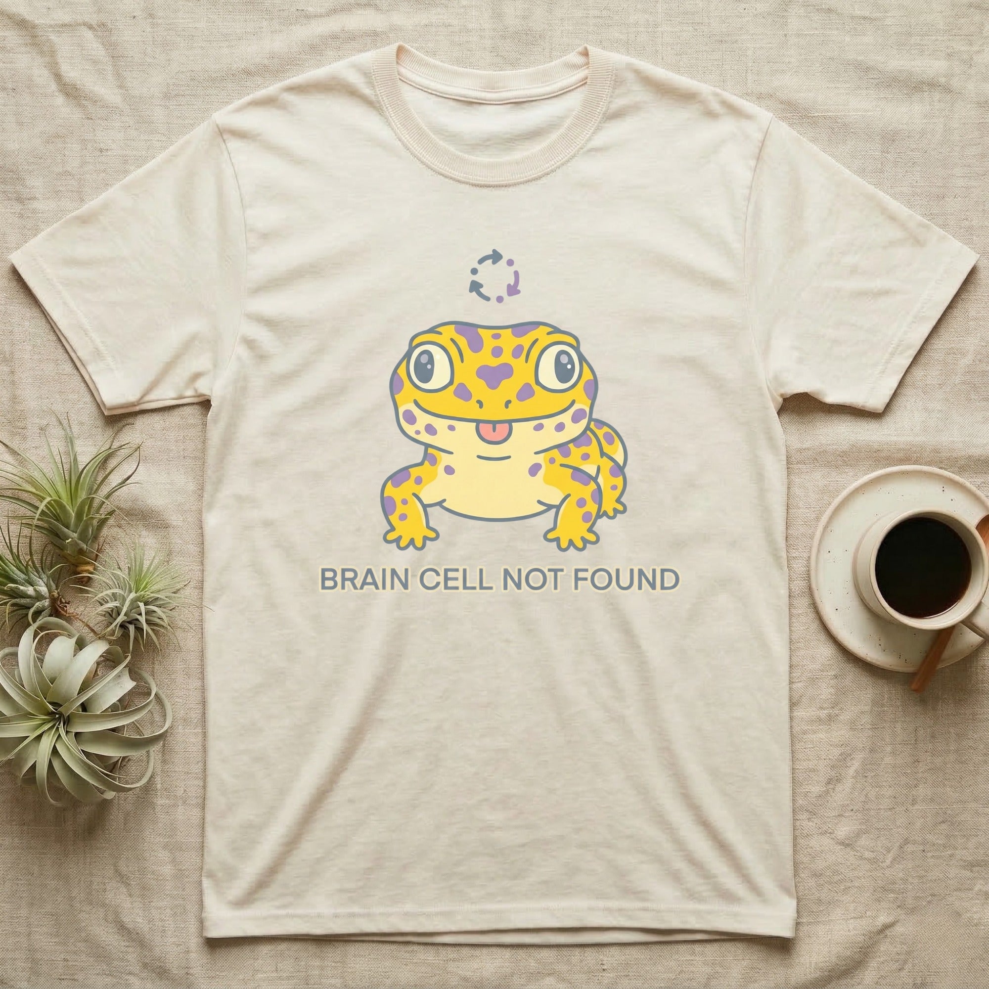 Cream t-shirt with yellow cartoon gecko and "BRAIN CELL NOT FOUND" text.