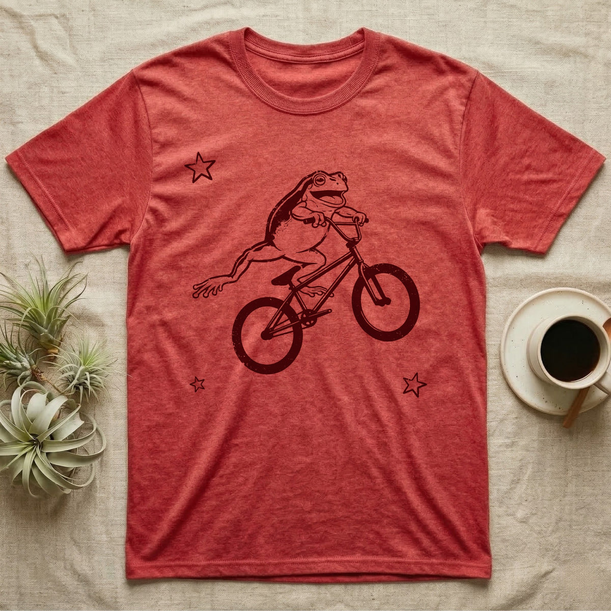 Tree Frog Can-Can T-Shirt in Heather Red — Distressed one-ink oxblood screenprint of a White's tree frog airborne on a BMX bike, both back legs kicked off the pedals and swung to one side, hands still on the bars.