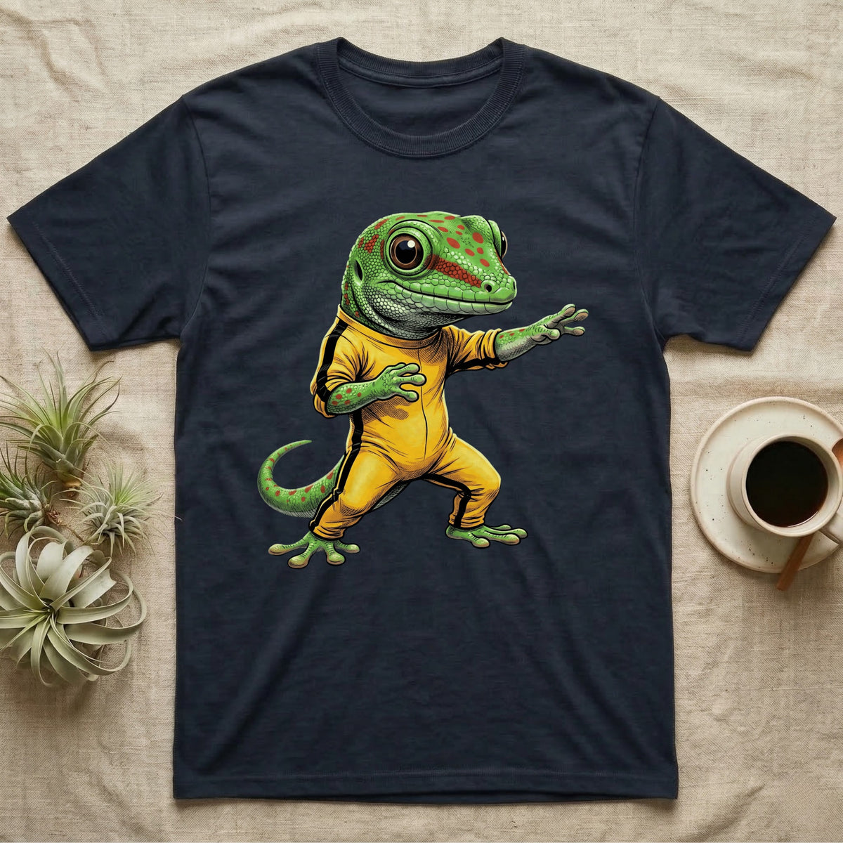 Anthropomorphic giant day gecko in a yellow-and-black martial-arts jumpsuit, low fighting stance, bold vintage-comic ink outlines and halftone shading, graphic-only design. — shown on a Navy tee.
