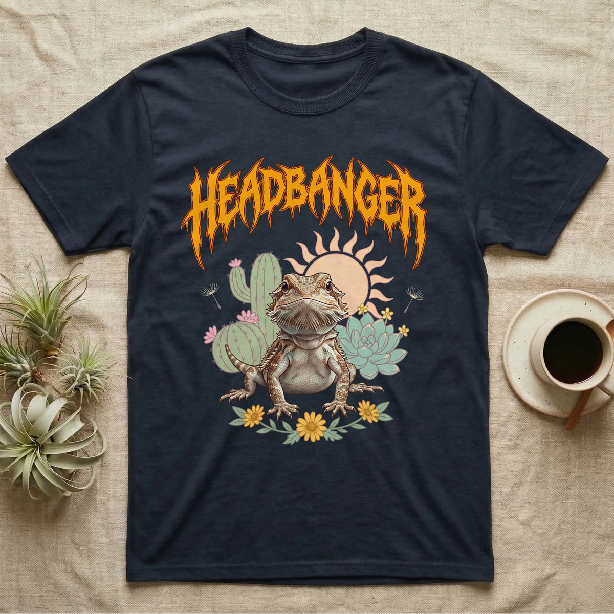 Central Bearded Dragon Feral T-Shirt in Navy — Baby bearded dragon in a pastel desert scene under a spiky amber metal wordmark reading HEADBANGER.
