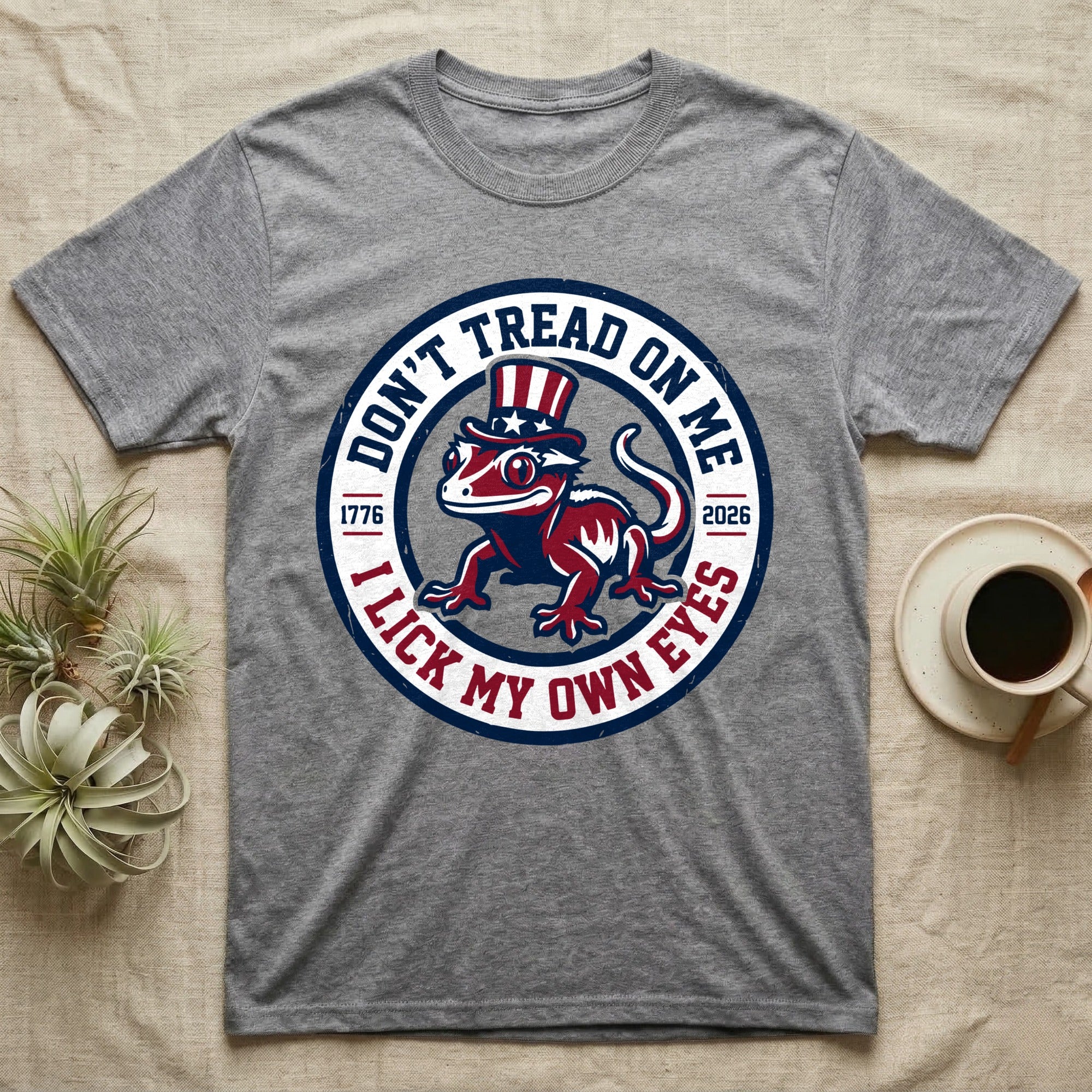 Crested Gecko 1776 T-Shirt in Sport Grey — Distressed crest of a crested gecko in a top hat with text Don't Tread On Me and I Lick My Own Eyes.