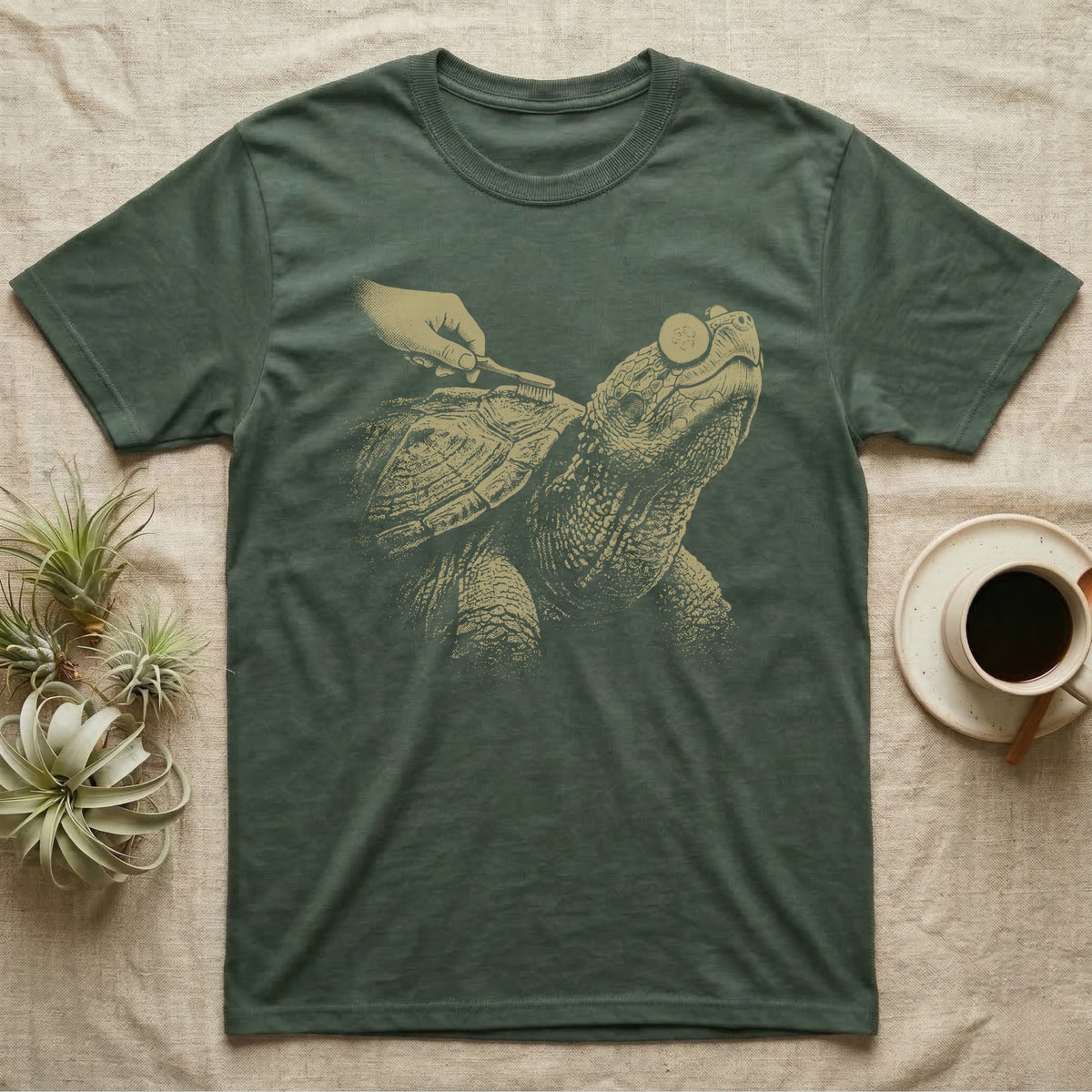 Snapping Turtle Spa T-Shirt in Military Green — Single-ink snapping turtle with cucumber slices on its eyes, chin up, while a hand scrubs its shell with a toothbrush.