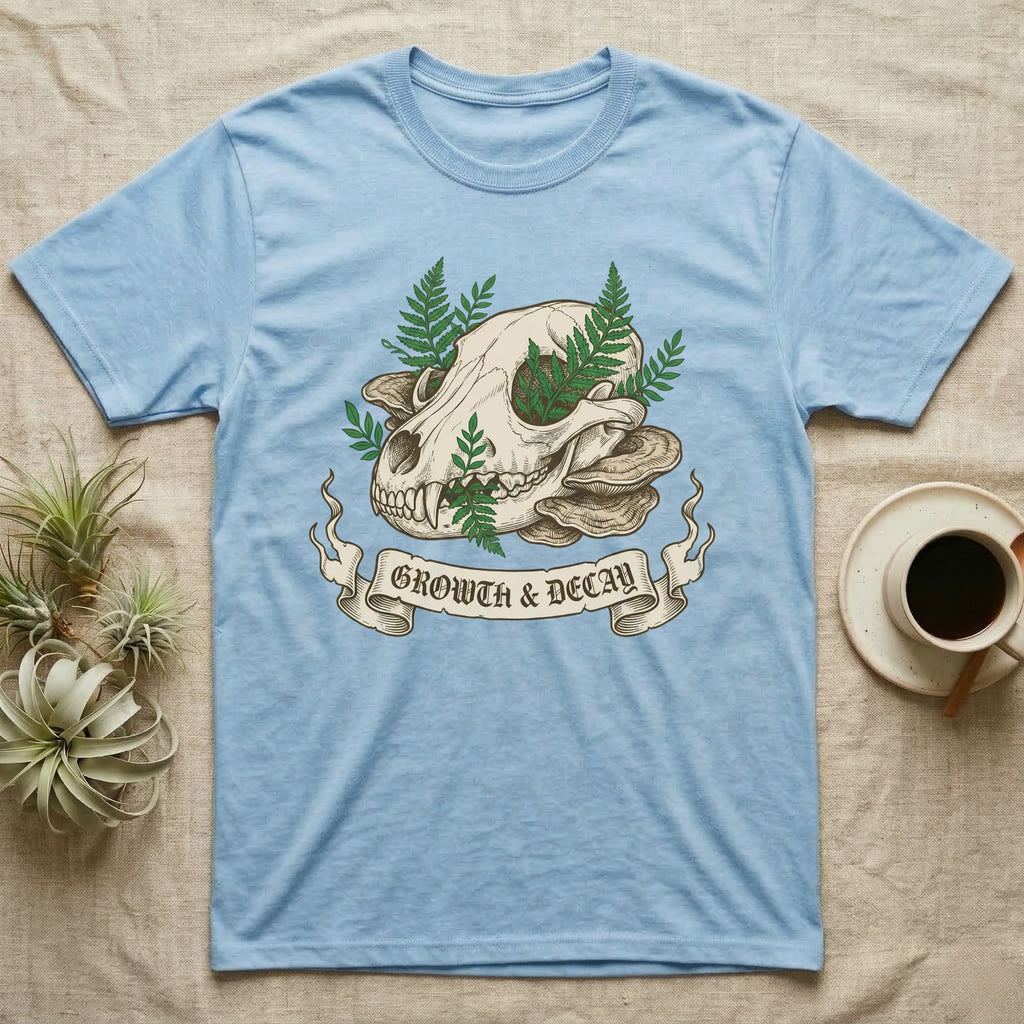 Light blue t-shirt with skull, ferns, and mushrooms, with "GROWTH & DECAY" banner.