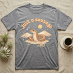 Kenyan Sand Boa Softie T-Shirt in Sport Grey — Kenyan sand boa looping out of pastel sand dunes under a puffy "just a sausage" bubble wordmark with tiny hearts.