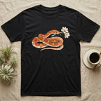 Corn Snake Blossom T-Shirt in Black — Watercolor illustration of an orange-and-cream corn snake holding a magnolia blossom sprig, on a dark grey t-shirt.