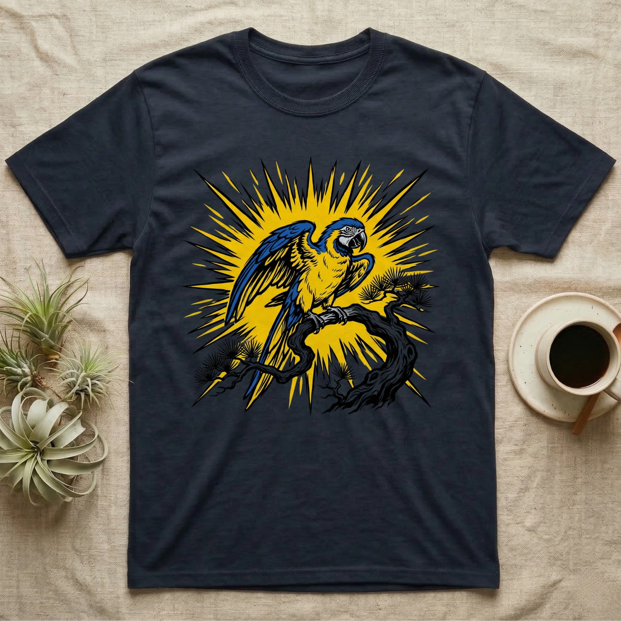 Dark t-shirt with a blue and yellow macaw perched on a branch, surrounded by a sunburst.