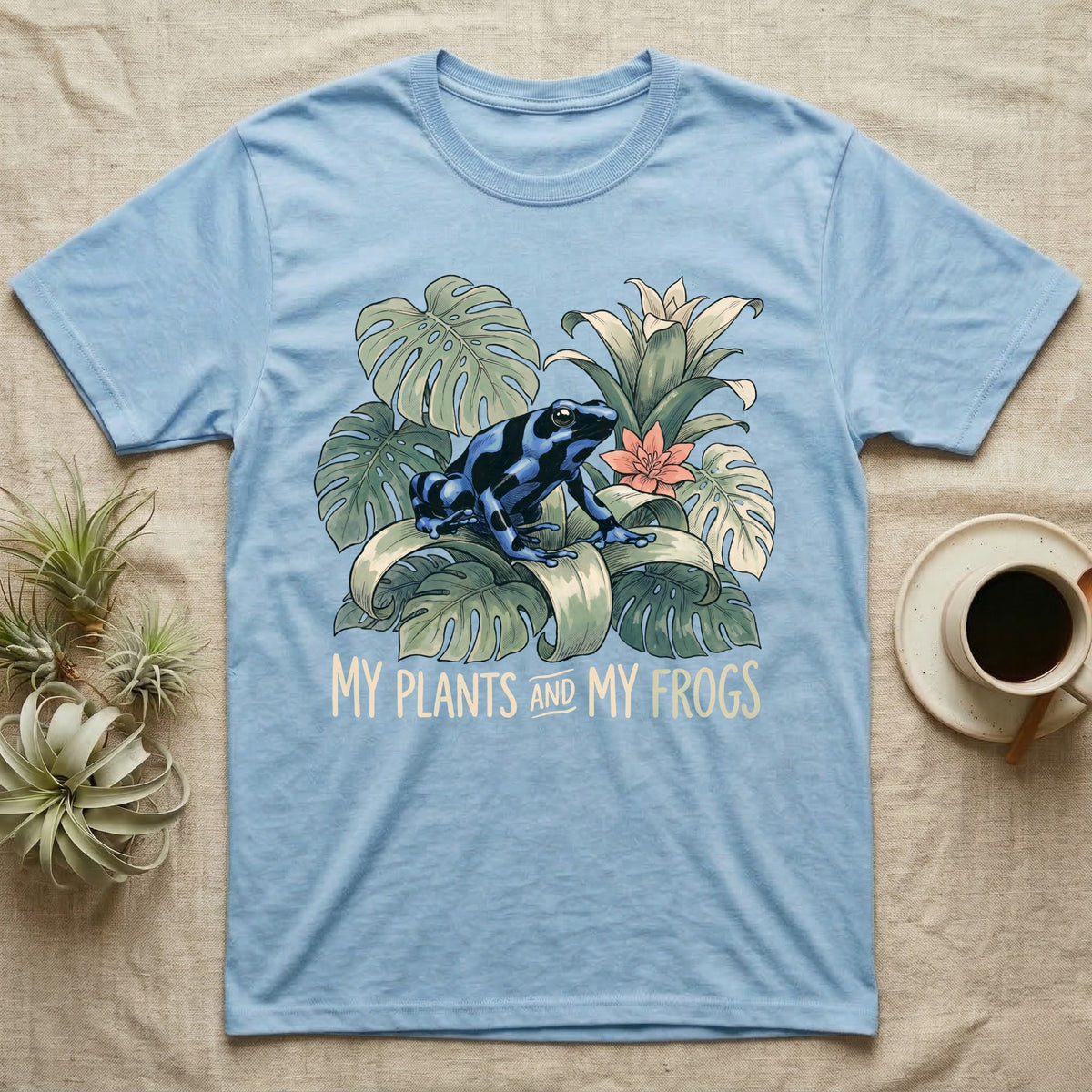 Plants And Frogs T-Shirt in Light Blue — Naturalist-plate illustration of a dart frog perched in lush foliage with hand-lettered text reading My Plants And My Frogs.