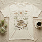 Western Hognose Home Range T-Shirt in Natural — Woodcut-style illustration of a western hognose snake nosing through sand with dunes and sagebrush behind, no on-shirt text.