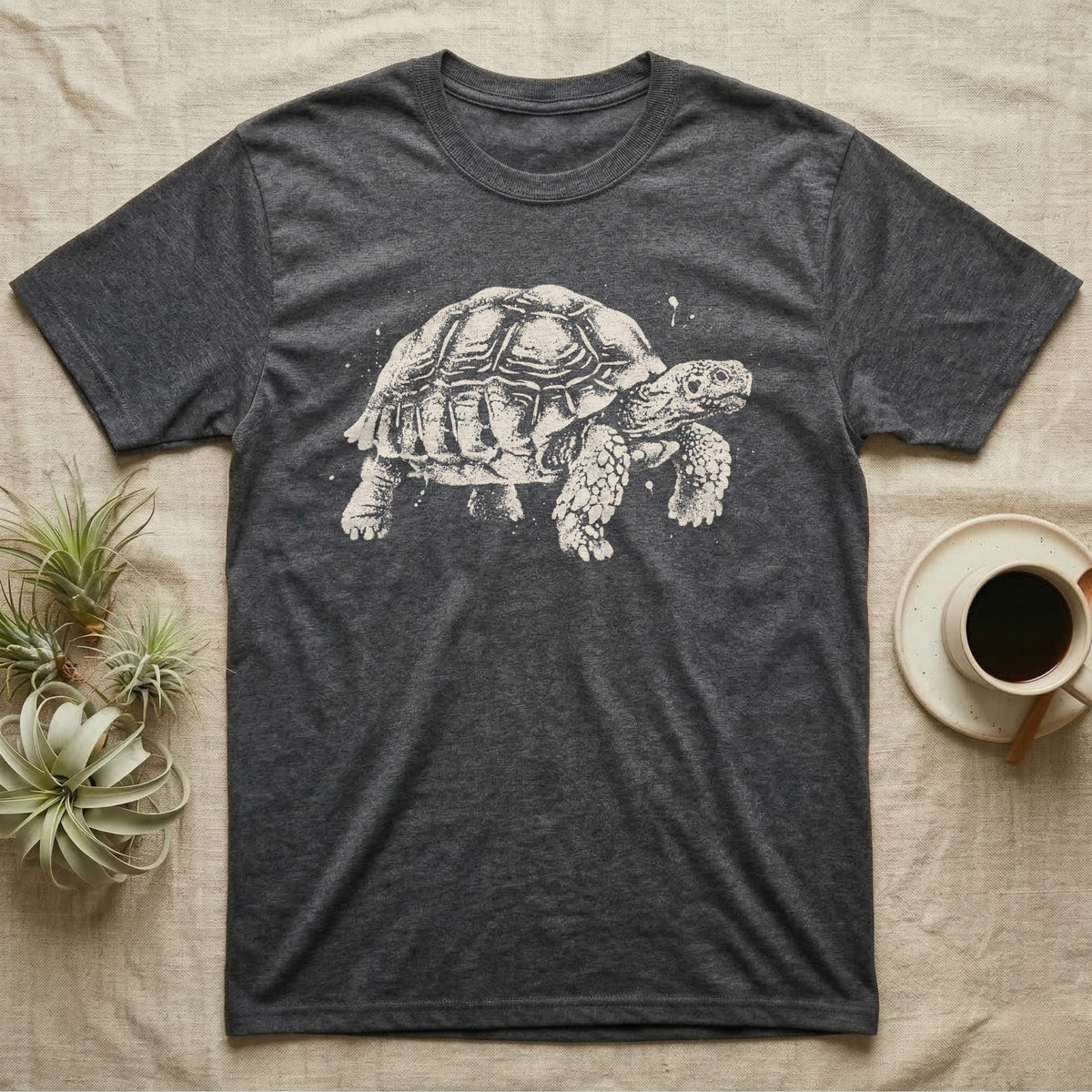 Sulcata Bleach Spatter T-Shirt in Dark Heather — Sulcata tortoise marching to the right, head up and one scaly front leg mid-step, formed from pale bleach spatter on black.