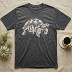 Sulcata Bleach Spatter T-Shirt in Dark Heather — Sulcata tortoise marching to the right, head up and one scaly front leg mid-step, formed from pale bleach spatter on black.