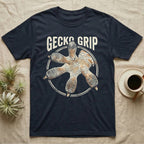 Macro badge illustration of a gecko's splayed foot with ribbed adhesive toe pads inside a distressed circular border, arched wordmark reading GECKO GRIP. — shown on a Navy tee.