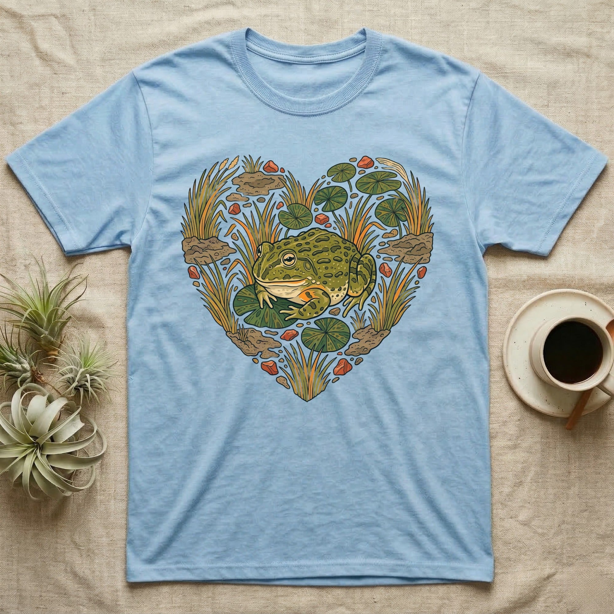 Light blue t-shirt with a frog and lily pads forming a heart design.