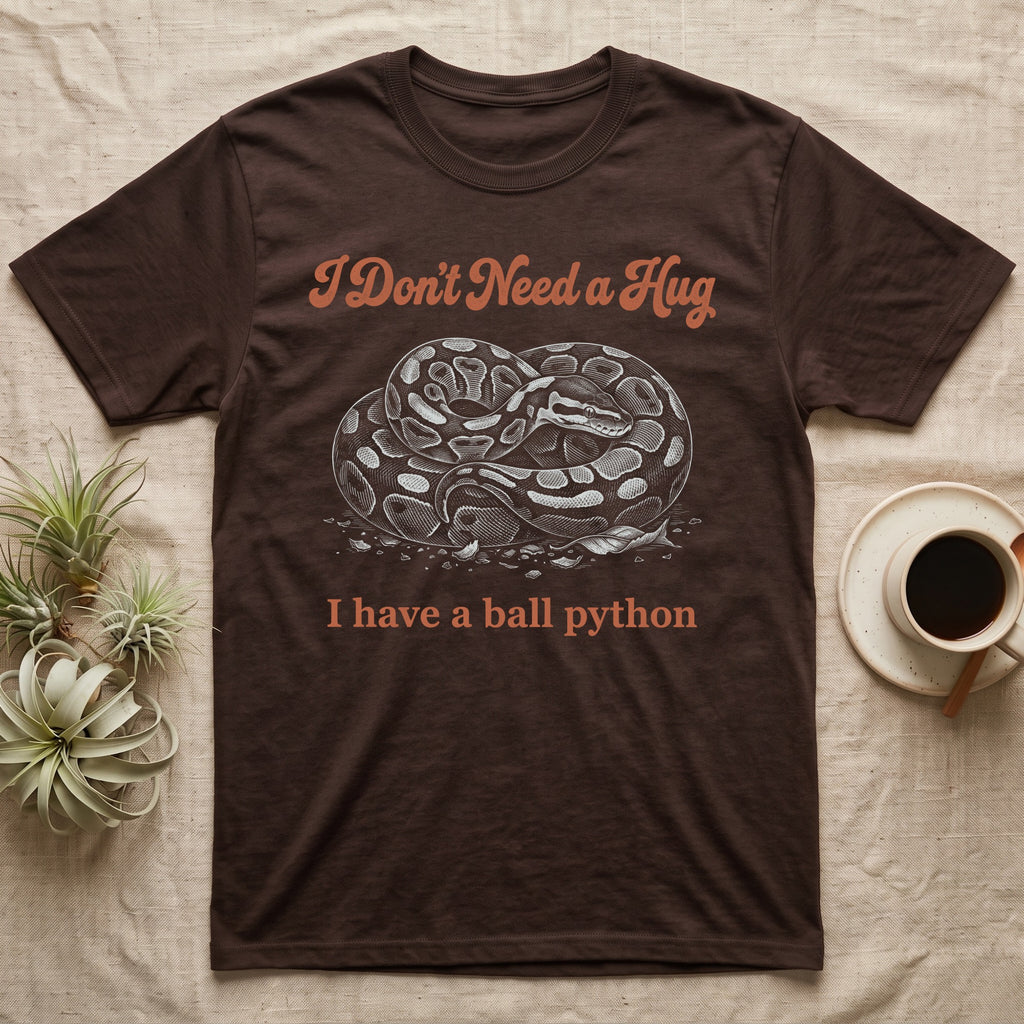 Ball Python Hug T-Shirt in Dark Chocolate — White-line engraving of a coiled ball python under orange script reading I Don't Need a Hug, I have a ball python