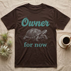 Box Turtle Owner T-Shirt in Dark Chocolate — White engraved eastern box turtle walking forward between the word Owner in teal script and for now in teal serif type.