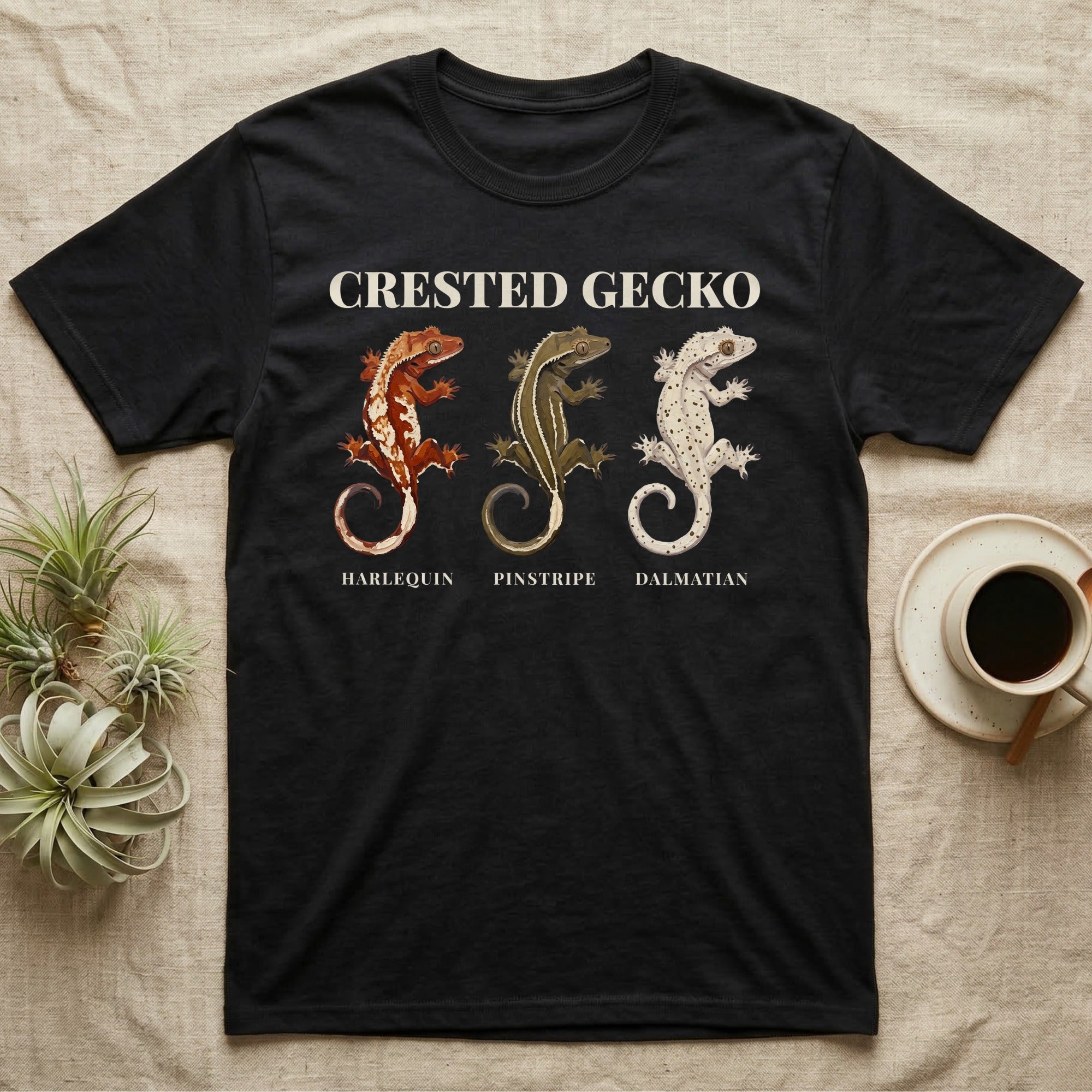 Crested Gecko Morph Chart T-Shirt in Black — Impasto painted chart of three crested gecko morphs — harlequin, pinstripe and dalmatian — labelled beneath each gecko.