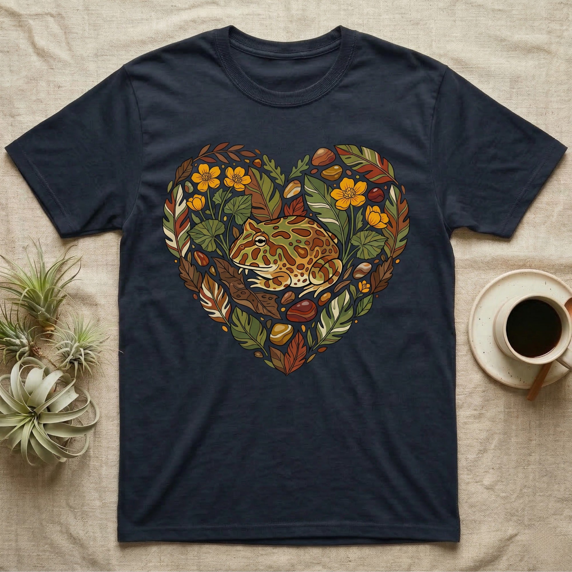 Dark t-shirt with heart-shaped design of a frog among leaves and flowers.
