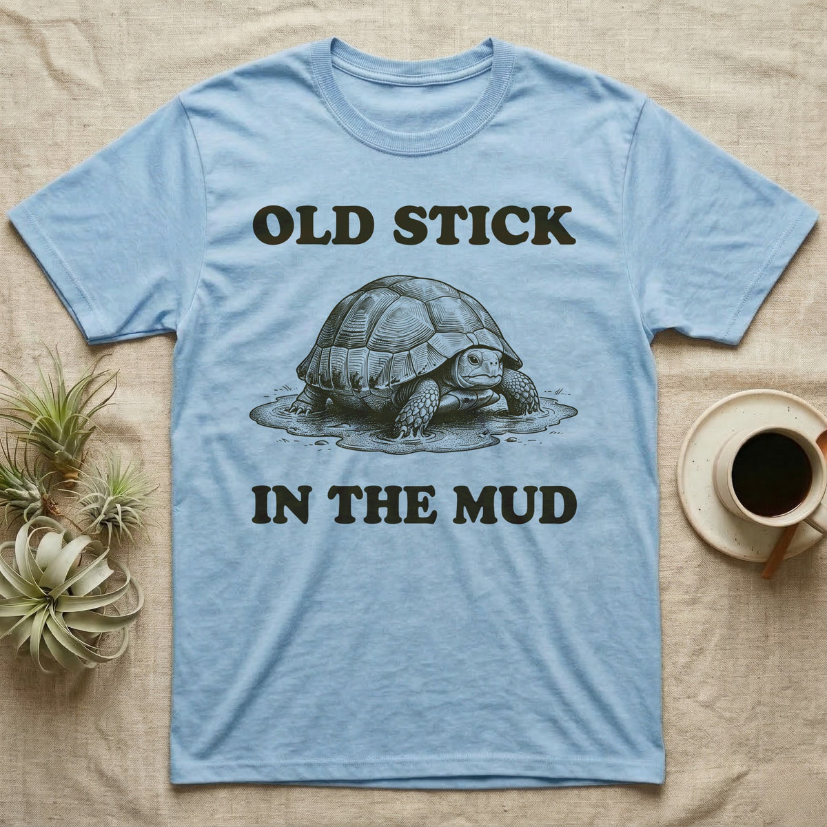 Hermann's Tortoise Mud T-Shirt in Light Blue — Engraved Hermann's tortoise sitting in a mud puddle, with the words Old Stick in the Mud