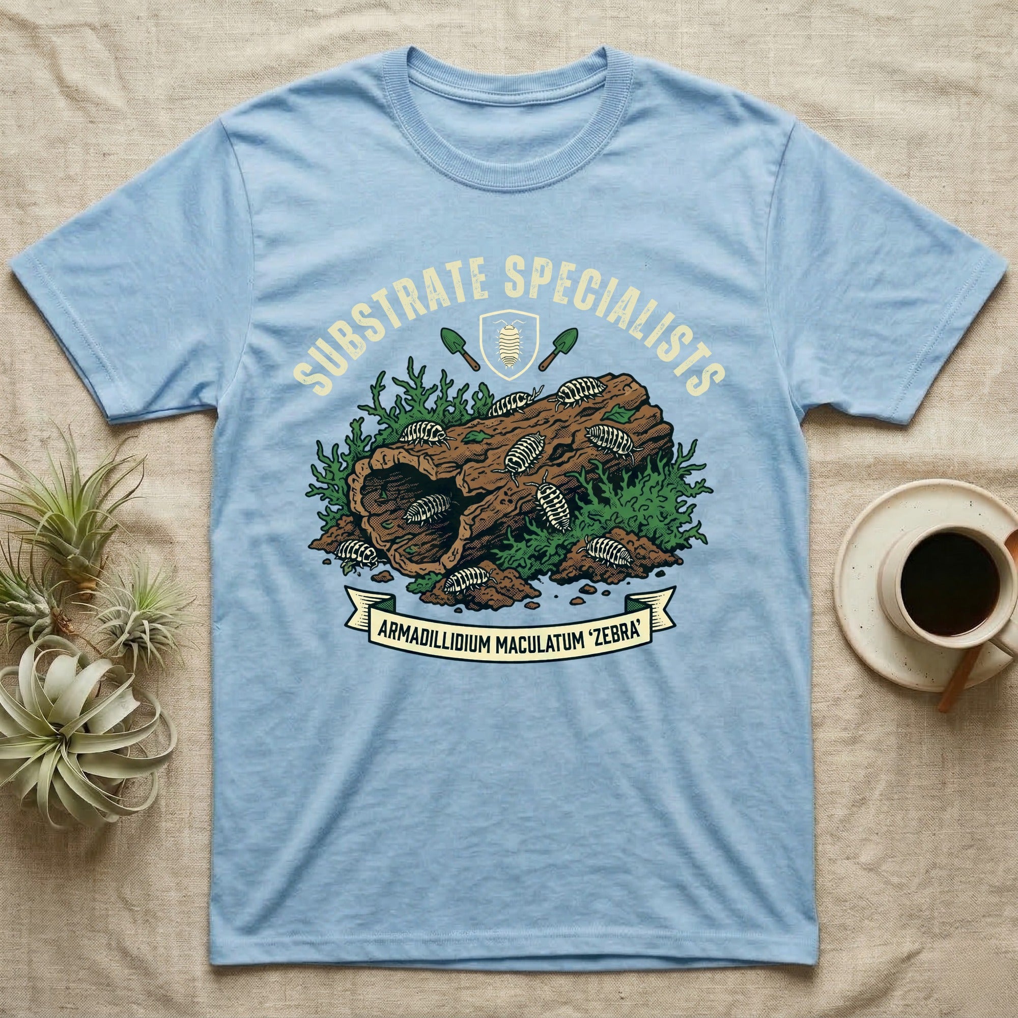 Zebra Isopod Substrate Specialists T-Shirt in Light Blue — Vintage crest of zebra isopods on a mossy cork log with crossed trowels and Armadillidium ribbon.