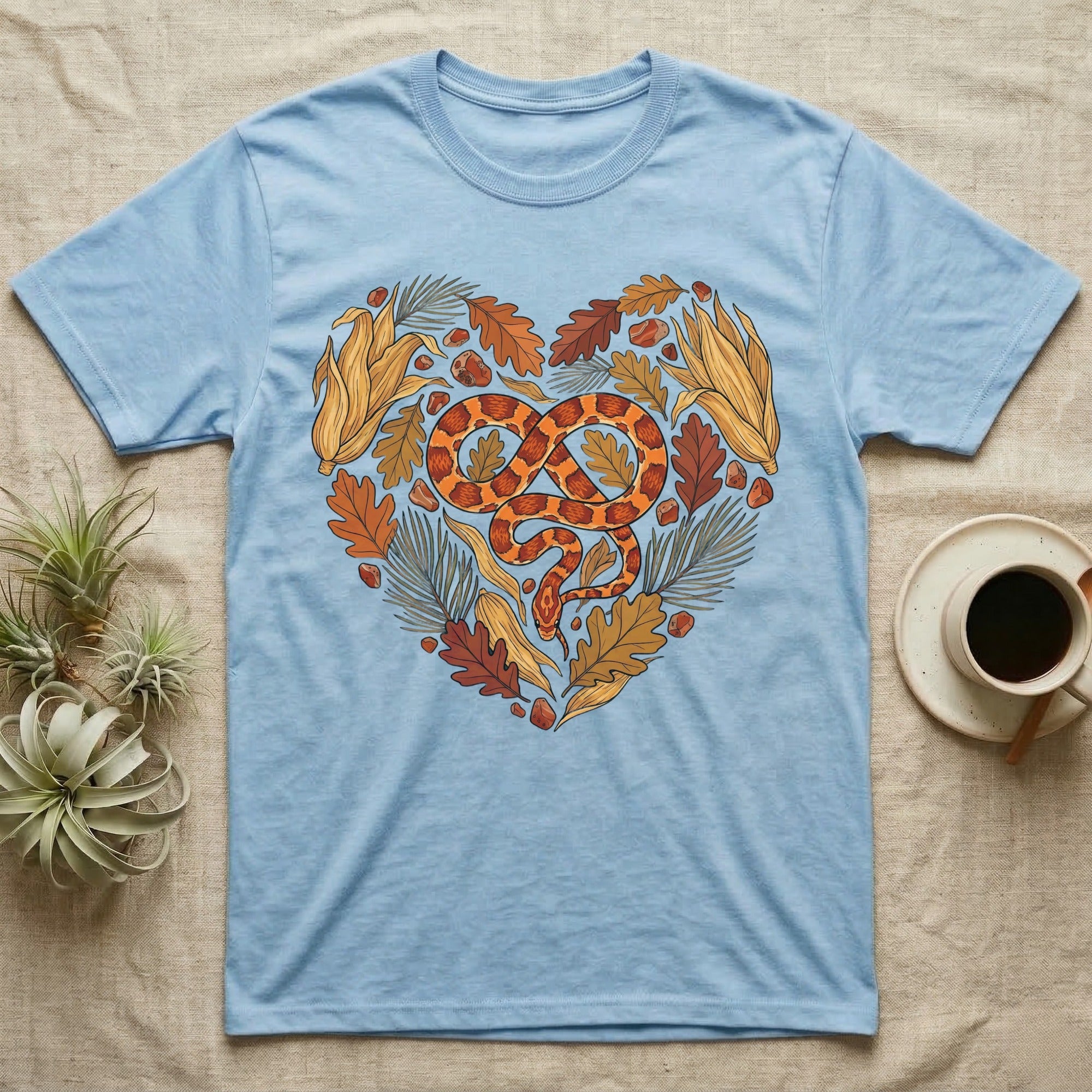 Light blue t-shirt with a heart-shaped snake and autumn leaves design.