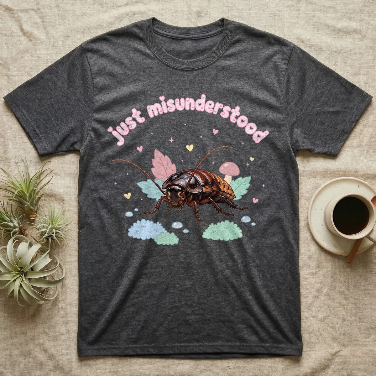 Madagascar Hissing Cockroach Baby T-Shirt in Dark Heather — Pastel Madagascar hissing cockroach among leaves, mushroom and moss, puffy pink wordmark "just misunderstood" above.