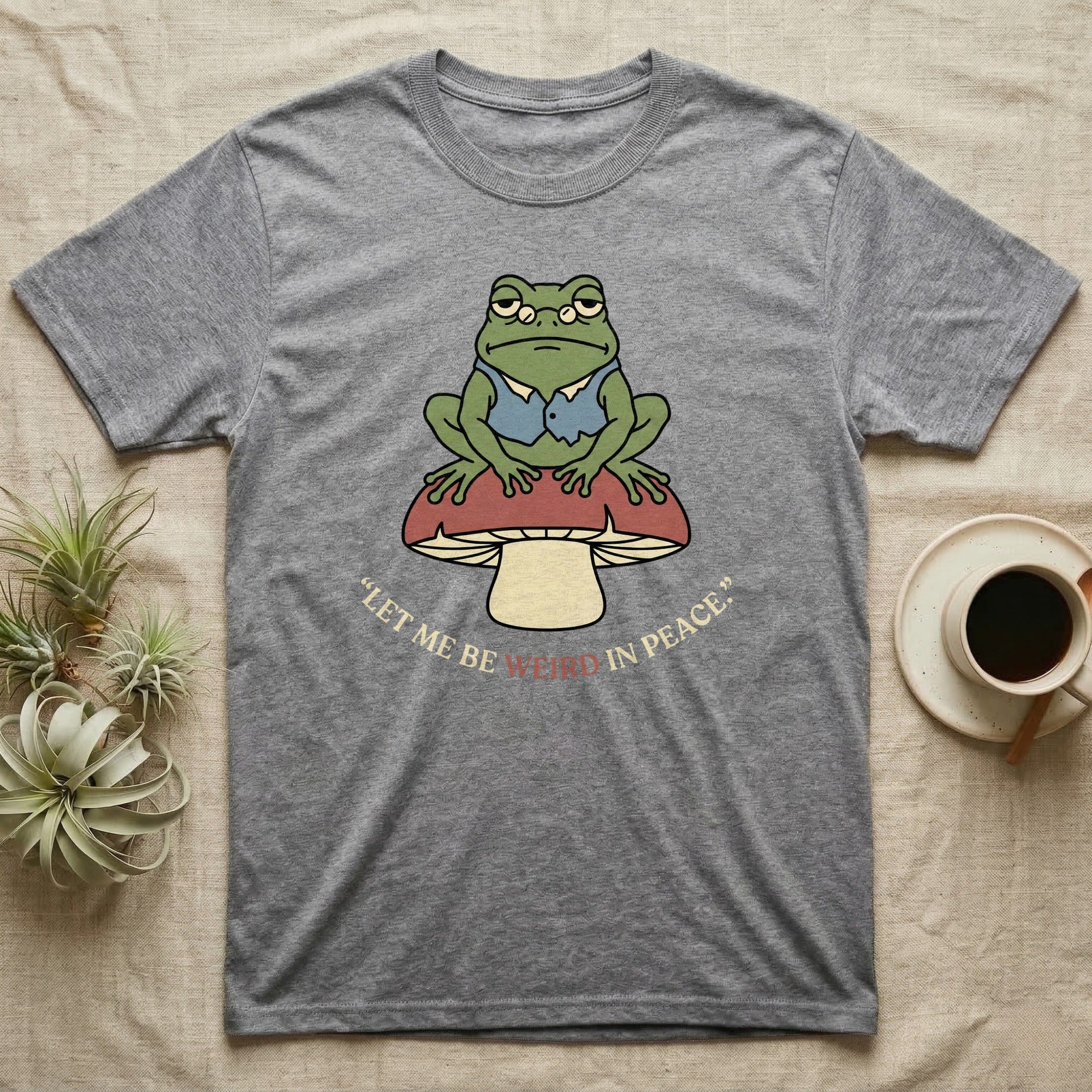 Grey t-shirt with frog on mushroom graphic and "Let me be weird in peace."