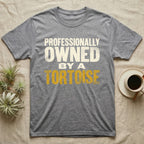 Owned By A Tortoise T-Shirt in Sport Grey — Distressed woodtype wordmark reading professionally owned by a tortoise in a bold two-tier lockup, text only.