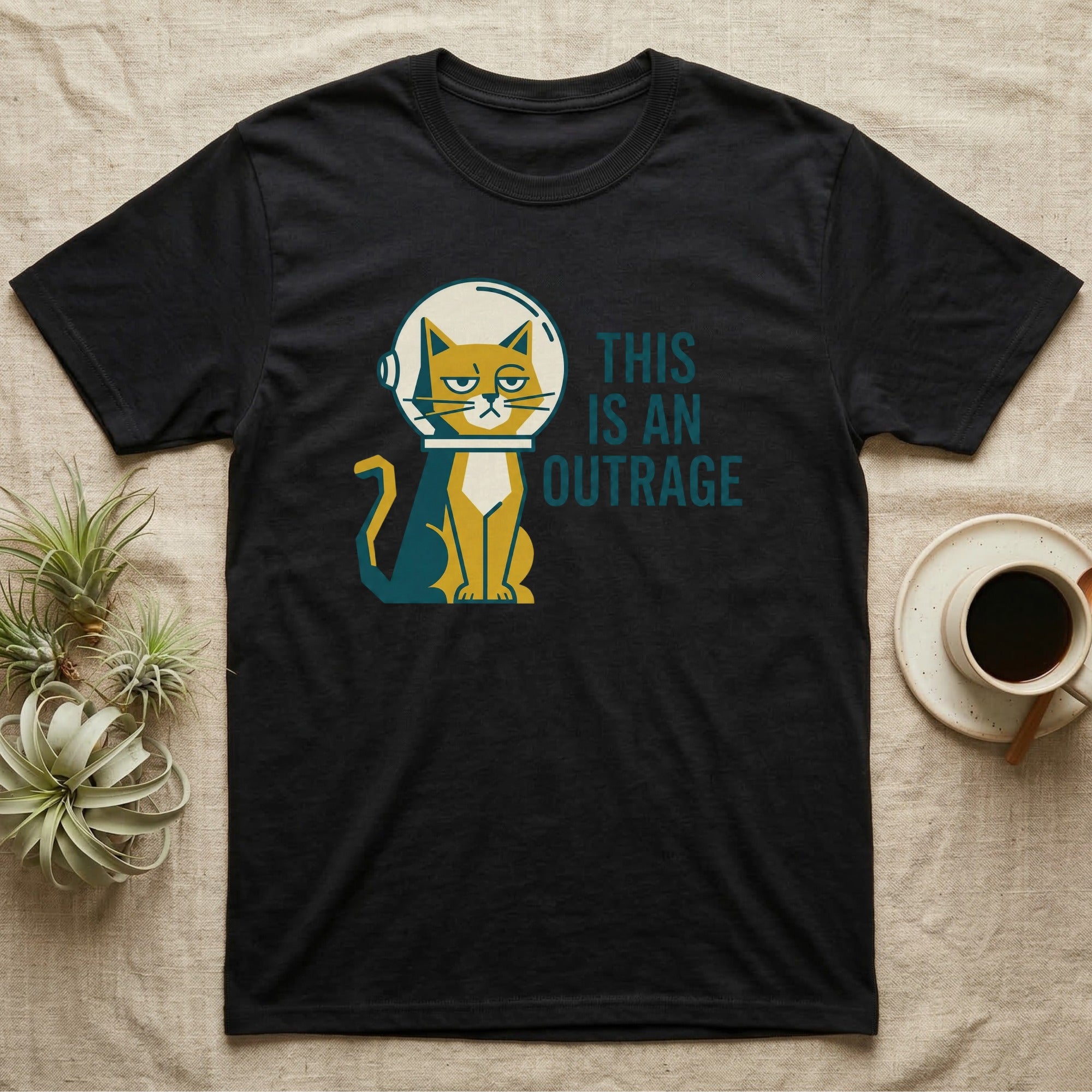 Black t-shirt with a cat in an astronaut helmet and the text "THIS IS AN OUTRAGE".