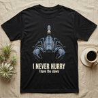 Flat-black mug-shot portrait of an emperor scorpion with claws spread toward the camera, with the printed words I Never Hurry, I have the claws. — shown on a Black tee.