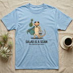 Bearded Dragon Salad Scam T-Shirt in Light Blue — Storybook-cartoon bearded dragon holding wilted greens at arm's length and a tub of roaches, captioned "Salad Is a Scam".