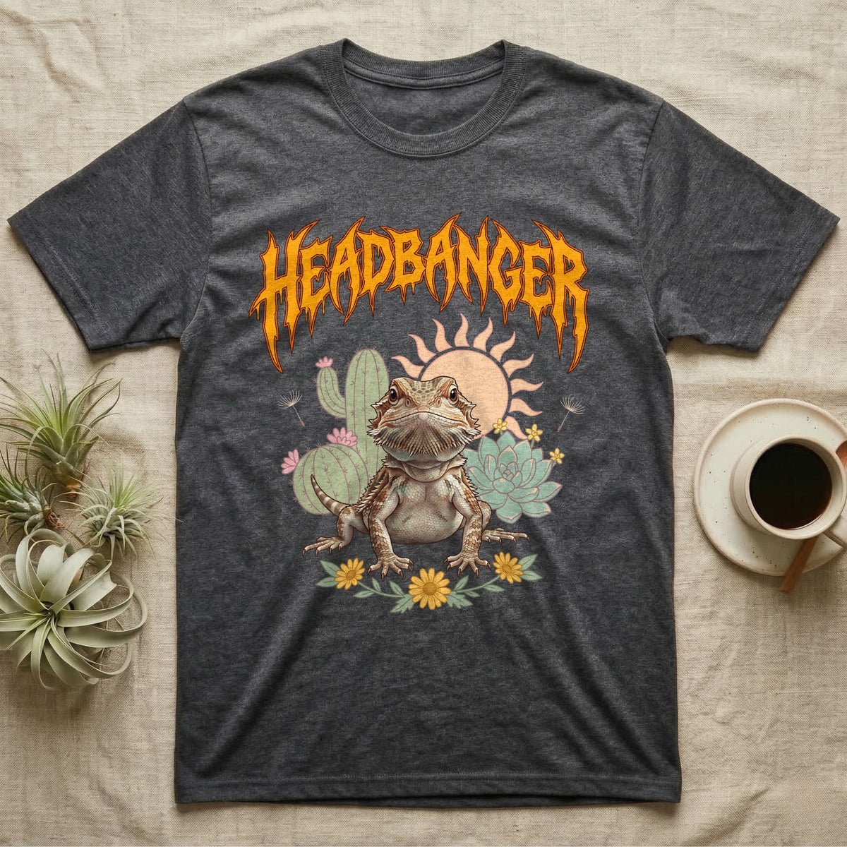 Central Bearded Dragon Feral T-Shirt in Dark Heather — Baby bearded dragon in a pastel desert scene under a spiky amber metal wordmark reading HEADBANGER.