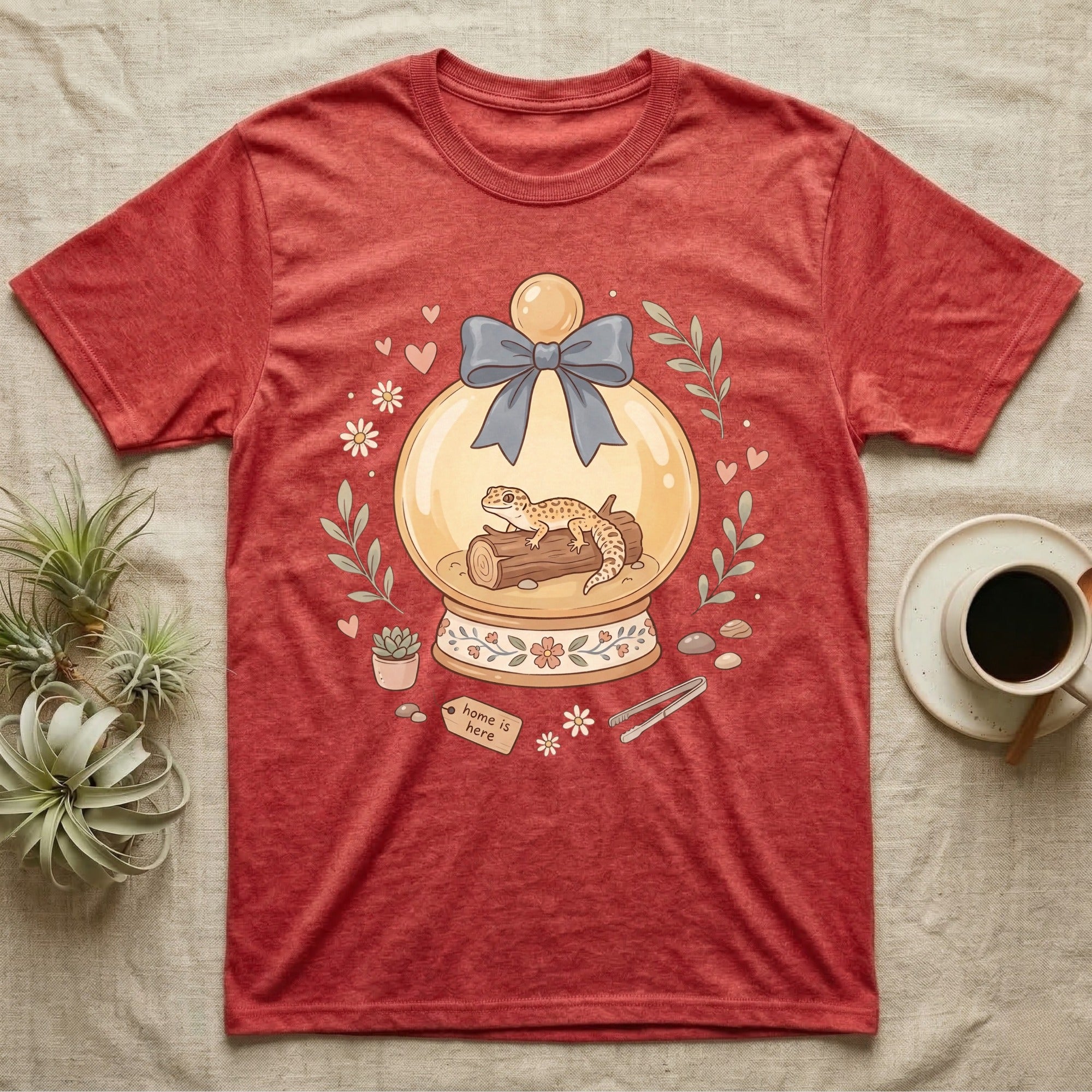 T-shirt with a leopard gecko in a snow globe with floral accents and "Home is here" tag.