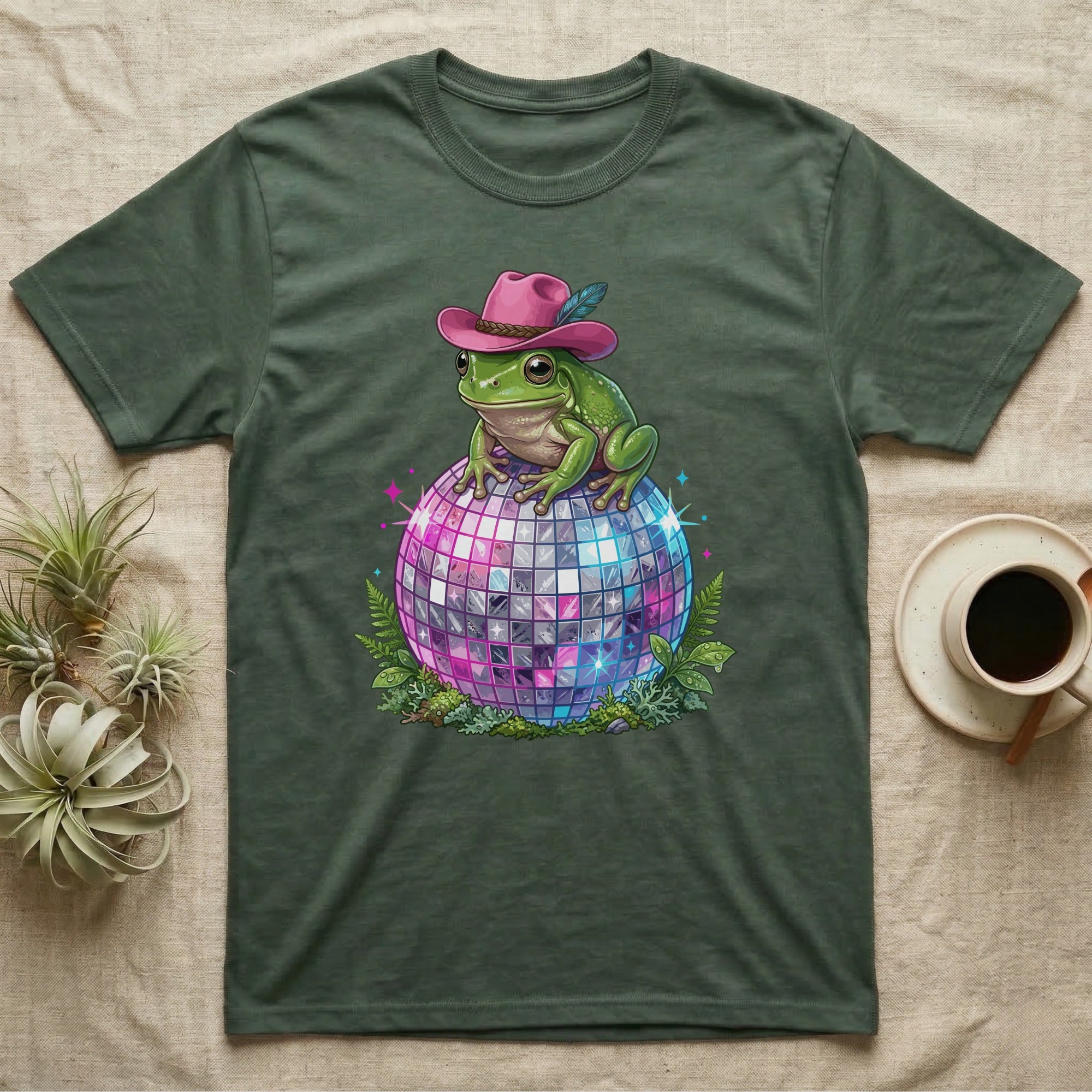 Green t-shirt featuring a cartoon frog in a pink cowboy hat on a disco ball.