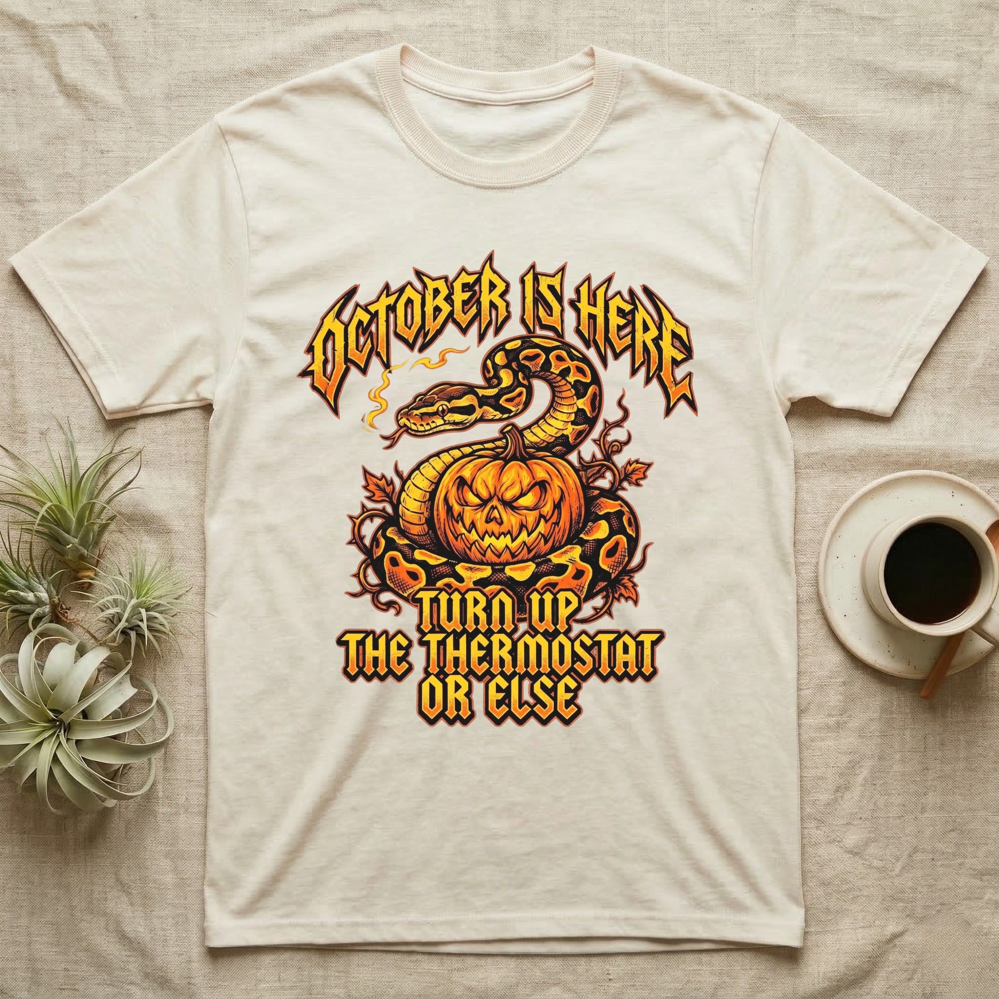 Ball Python October Thermostat T-Shirt in Natural — Metal-band style ball python coiled over a glowing jack-o'-lantern, "October Is Here, Turn Up the Thermostat Or Else."