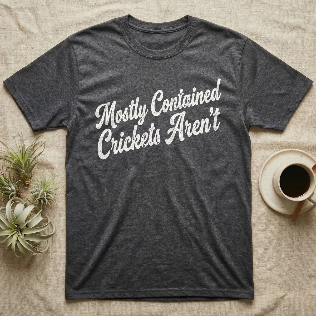 Reptile Cricket Escape T-Shirt in Dark Heather — Distressed off-white 1970s brush script reading Mostly Contained, Crickets Aren't, climbing a diagonal on charcoal grey