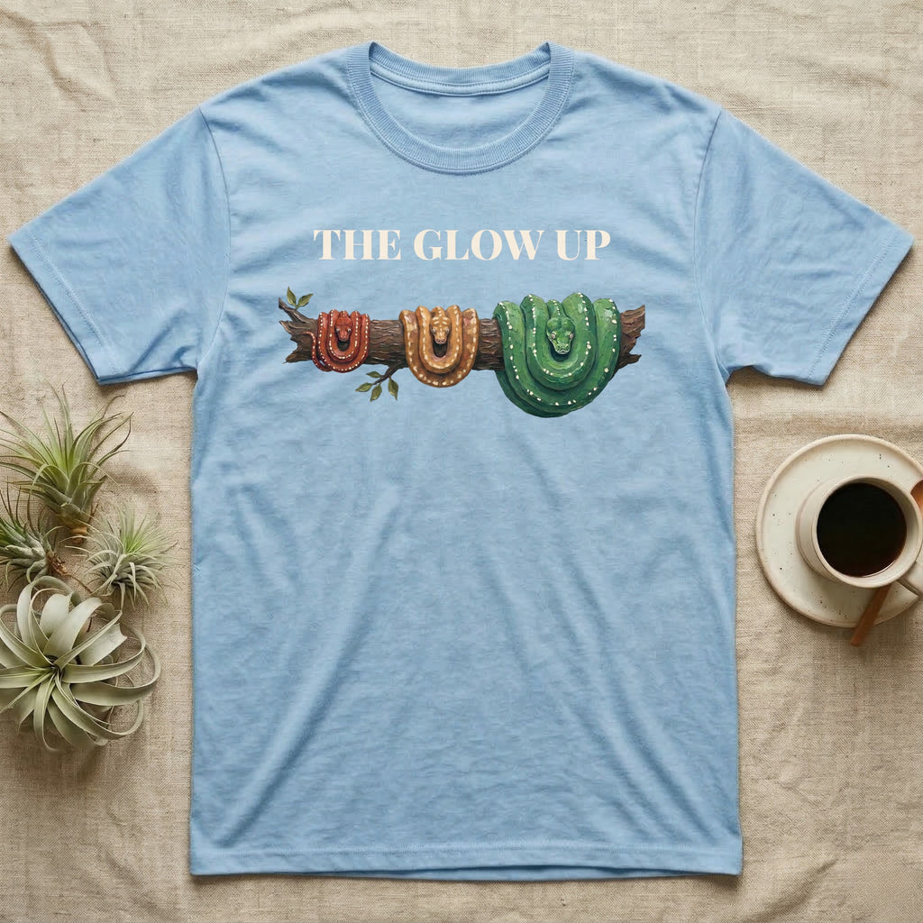 Green Tree Python Glow-Up T-Shirt in Light Blue — Impasto illustration of a green tree python at three life stages on one branch: red hatchling, orange-brown subadult, green adult.
