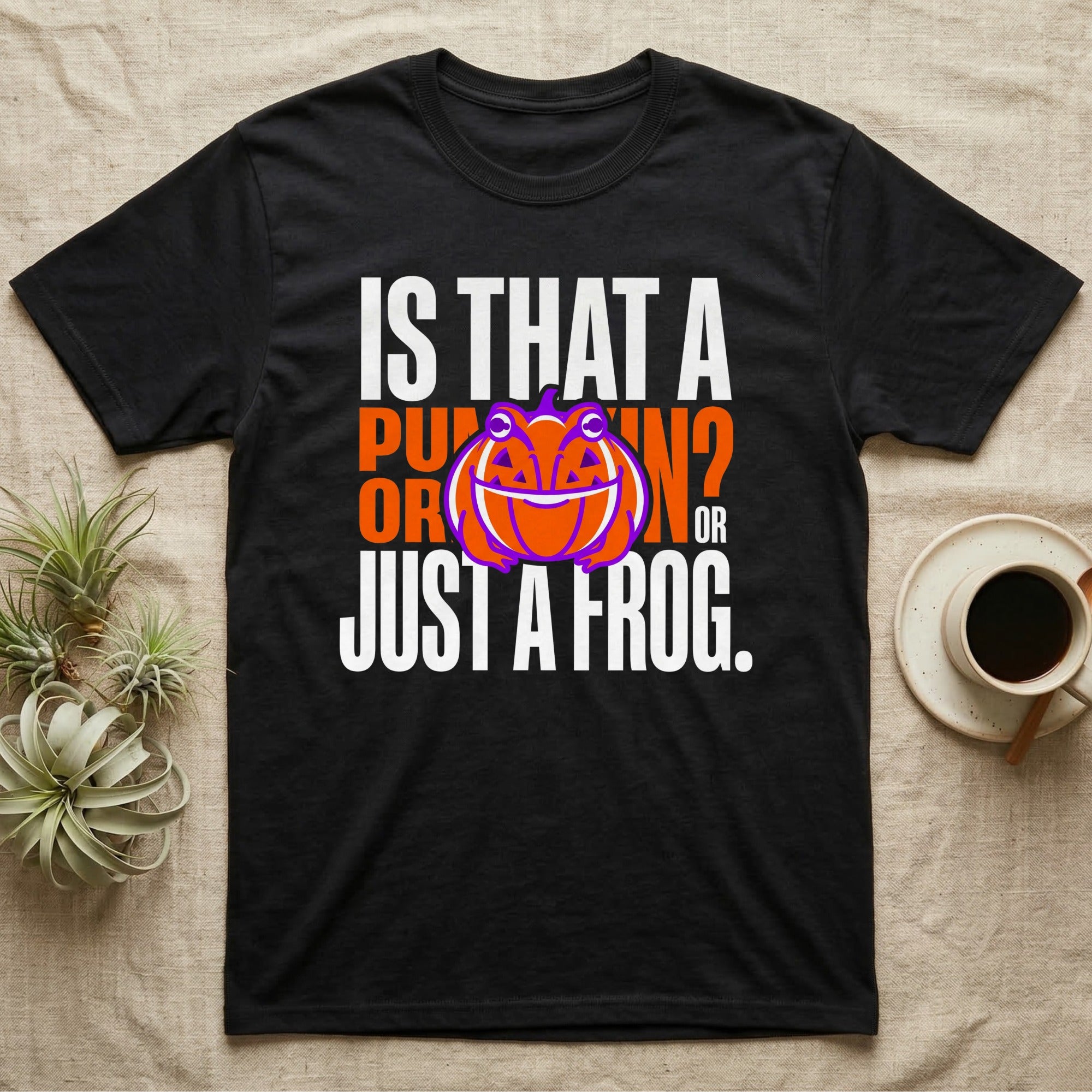 Frog Jack-O'-Lantern Illusion T-Shirt in Black — Typographic graphic of an orange frog doubling as a jack-o'-lantern, "Is That a Pumpkin? Or Just a Frog."