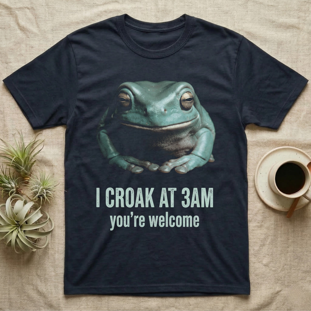 Deadpan photographic mugshot of a White's tree frog seated with folded hands above the distressed text I Croak At 3AM, you're welcome. — shown on a Navy tee.