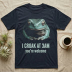 Deadpan photographic mugshot of a White's tree frog seated with folded hands above the distressed text I Croak At 3AM, you're welcome. — shown on a Navy tee.