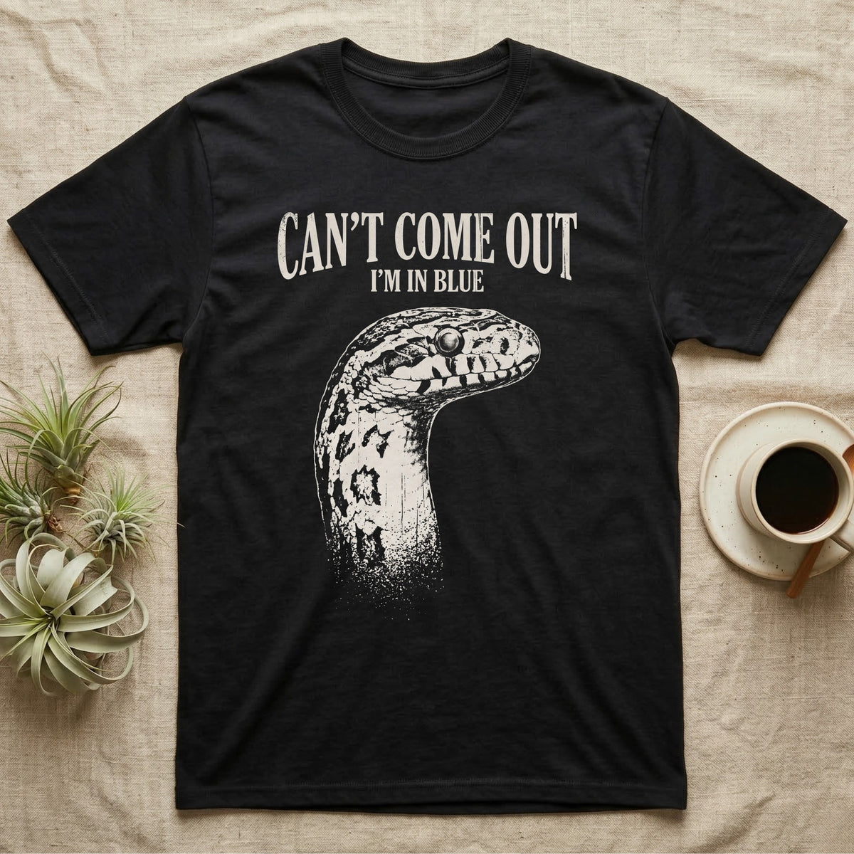 Corn Snake Shed T-Shirt in Black — Gritty white print of a corn snake head with milky pre-shed eyes under CAN'T COME OUT, I'M IN BLUE, on black