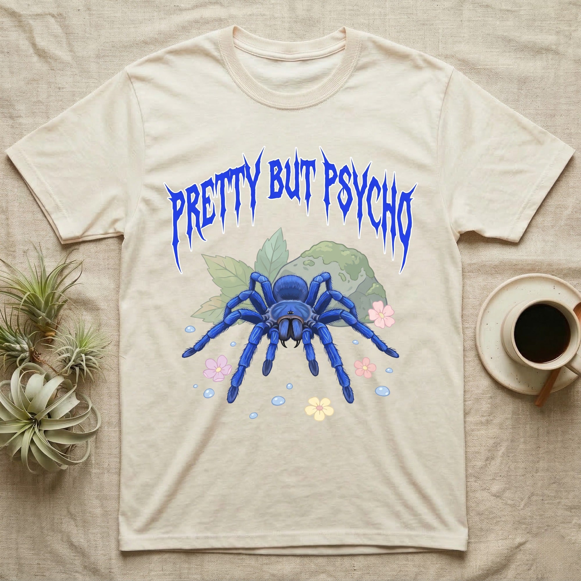 Cobalt Blue Tarantula Feral T-Shirt in Natural — Cobalt blue tarantula with electric-blue legs under jagged cobalt metal text PRETTY BUT PSYCHO with pastel blossoms