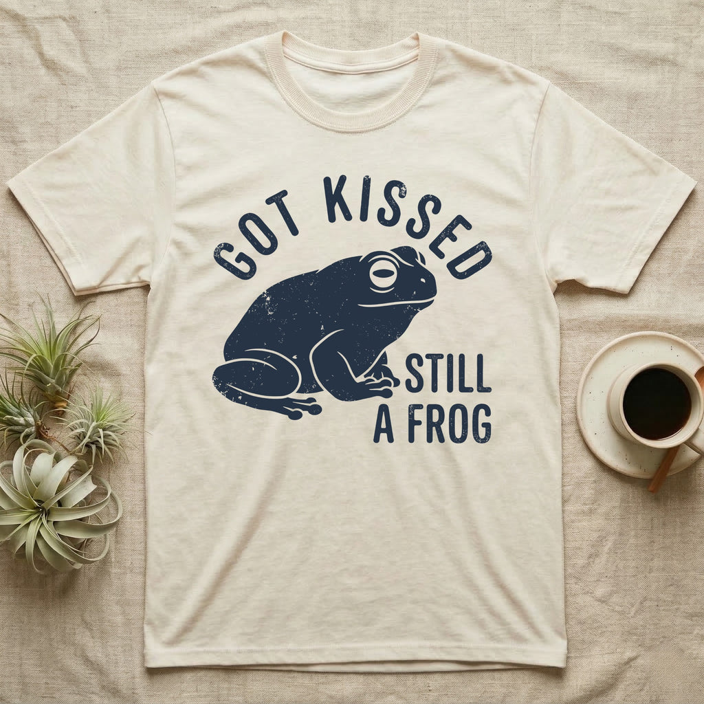 Tree Frog Kissed T-Shirt in Natural — Worn navy silhouette of a dumpy White's tree frog under the words Got Kissed Still A Frog