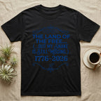 Corn Snake Still Missing Tee in Black — Royal blue typographic tee reading The land of the free but my snake is still missing, with Victorian filigree and small coiled corn snakes.