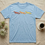 Uromastyx Colour Morph Trio T-Shirt in Light Blue — Three uromastyx lizards in a row, painted in thick raised relief — brick red, tangerine orange and lemon yellow morphs.