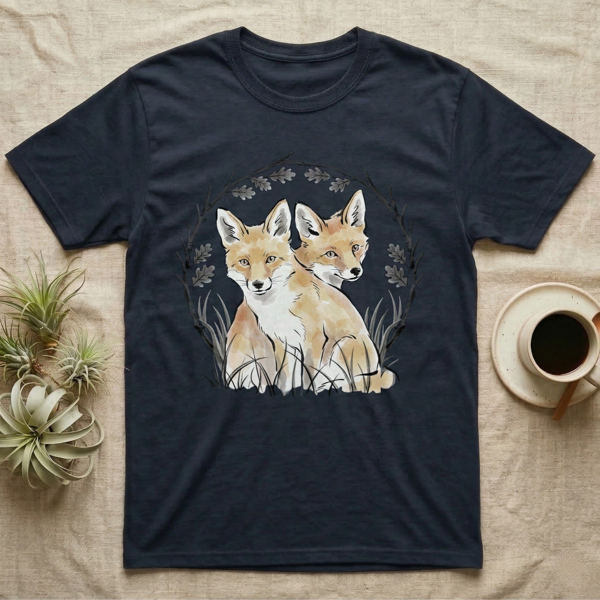 Dark t-shirt with a circular design of two foxes and foliage.