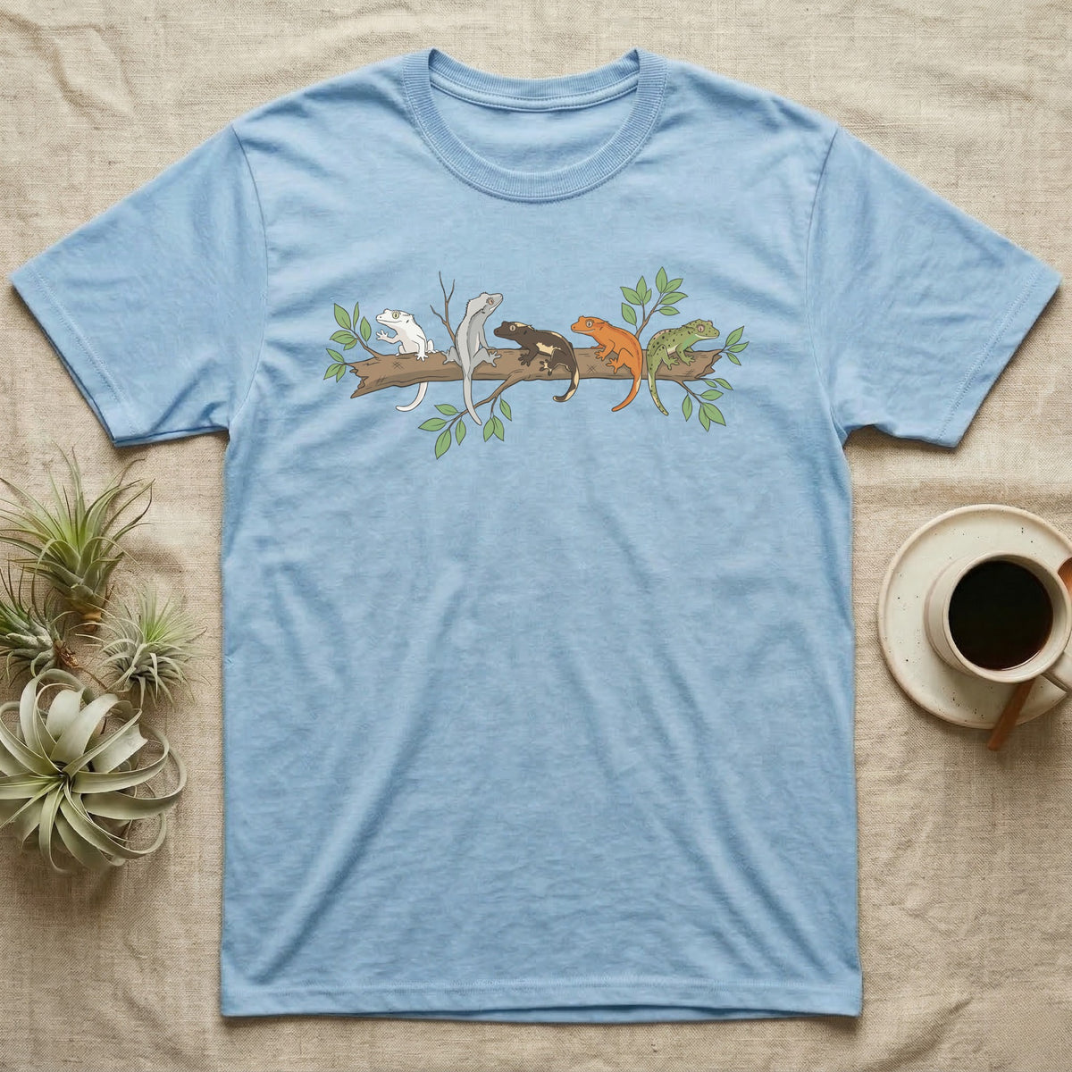Crested Gecko Morph Line T-Shirt in Light Blue — Five crested gecko morphs in ink and watercolour perched along one cork bark branch with ficus leaves.